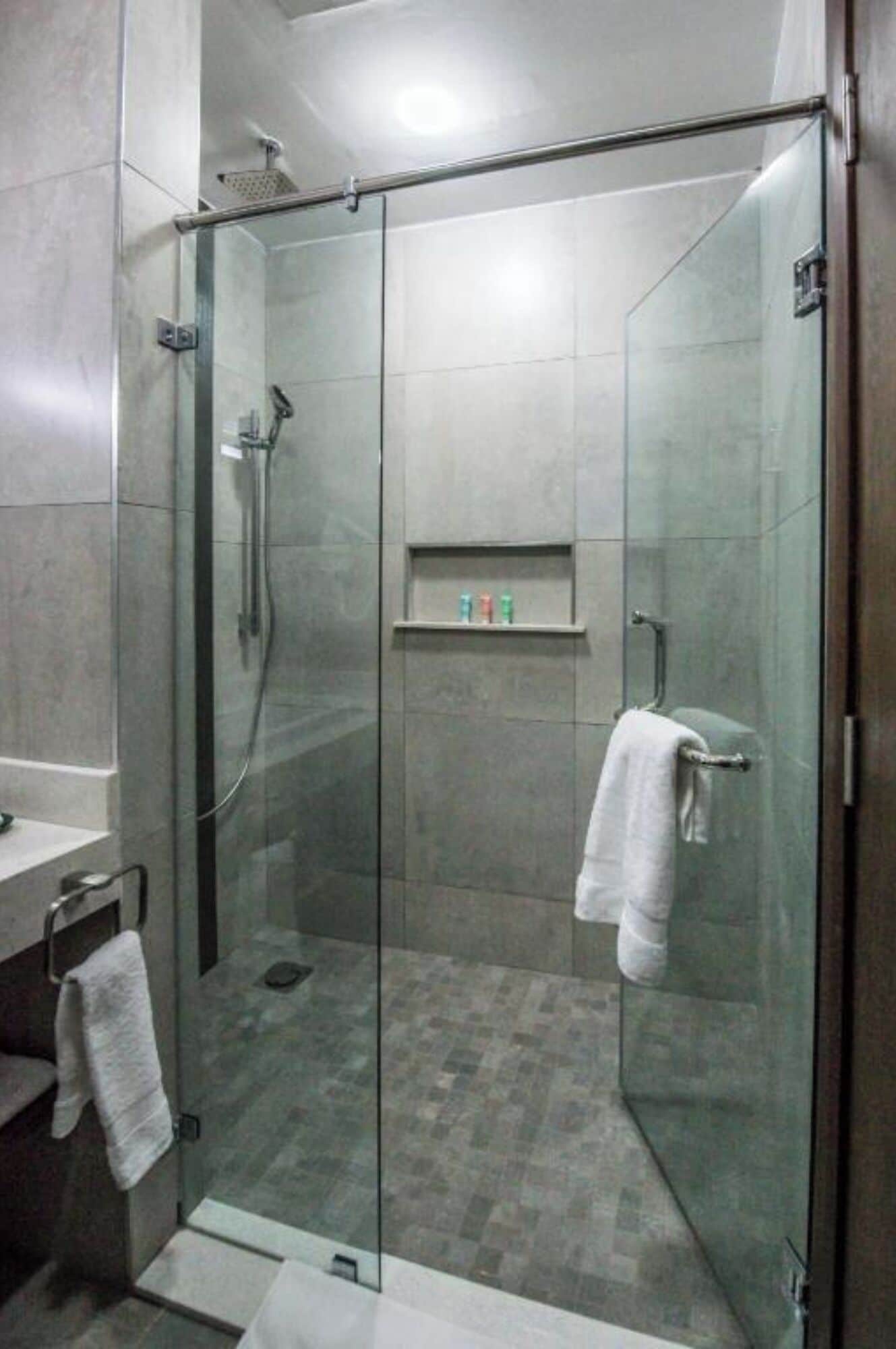 Un bagno moderno con cabina doccia in vetro, lavandino bianco e porta asciugamani.