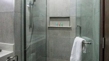 Un bagno moderno con cabina doccia in vetro, lavandino bianco e porta asciugamani.