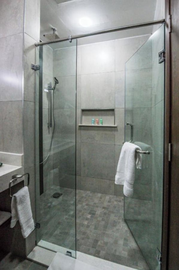 A modern bathroom with a glass-enclosed shower, a white sink, and a towel rack.