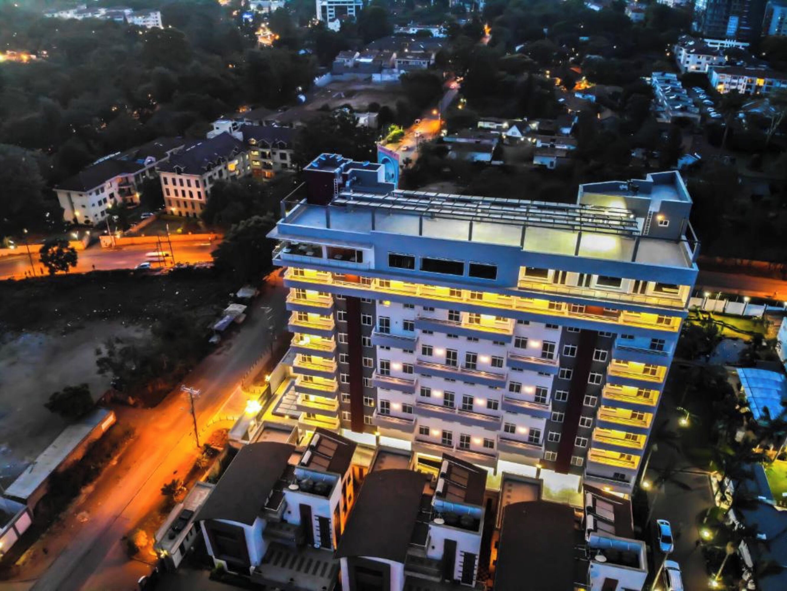 Un hôtel à plusieurs étages au design moderne, doté de balcons à chaque niveau et d’une terrasse sur le toit.