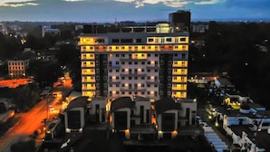 Een hotel met meerdere verdiepingen en een centrale binnenplaats, omringd door andere gebouwen.