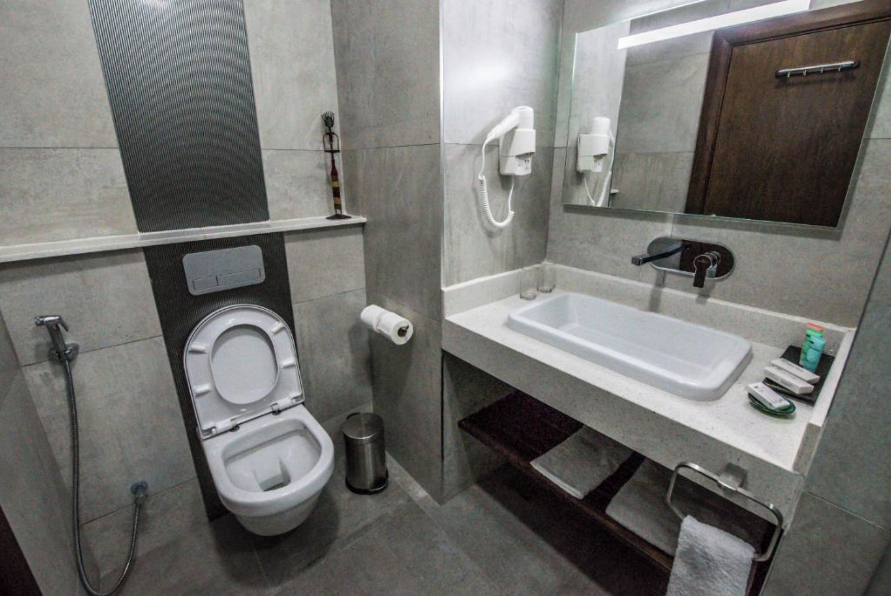 A modern bathroom with a toilet, bidet, and a sink with a mirror above it.