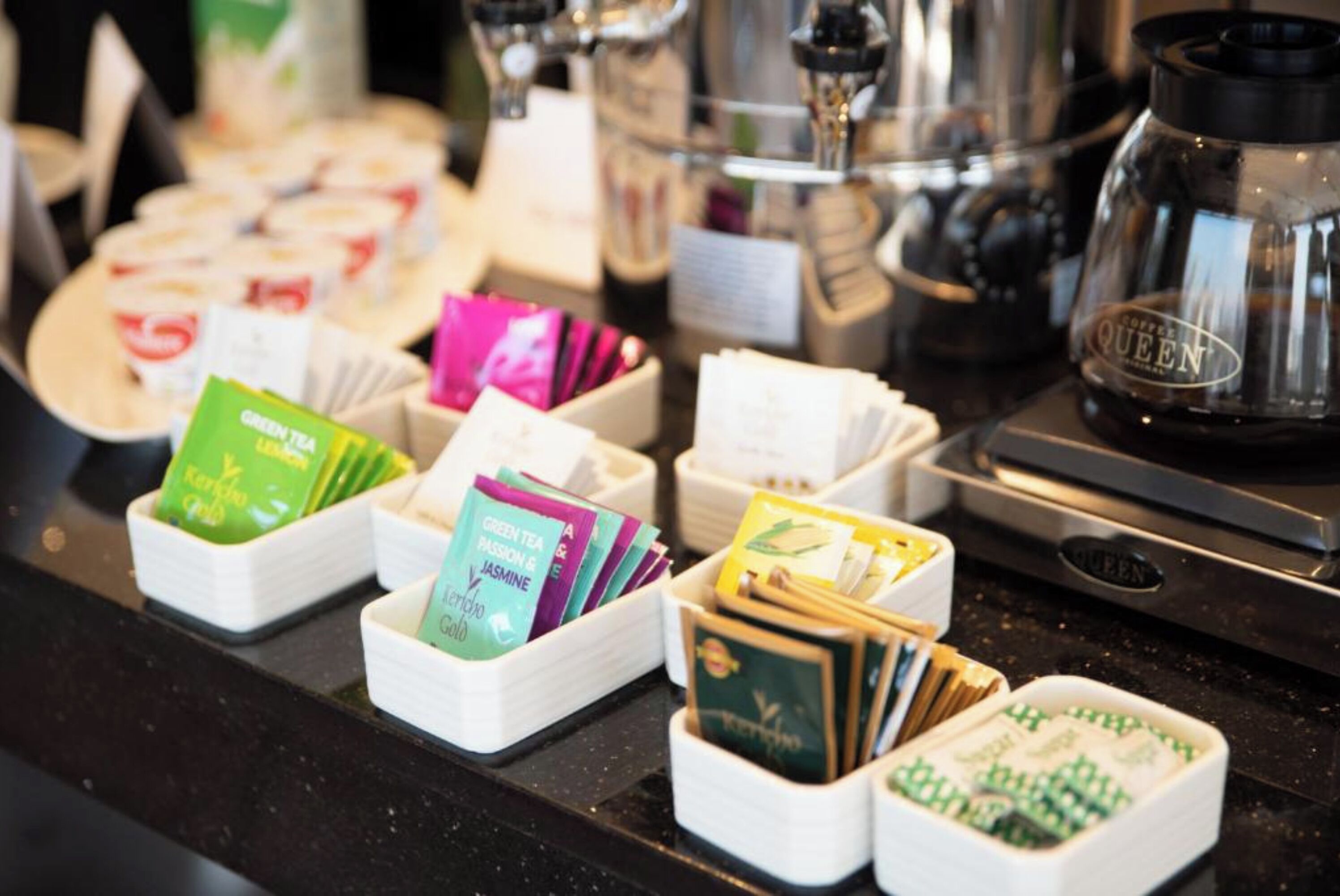 A coffee station with various tea and coffee products, including branded boxes and a coffee maker.