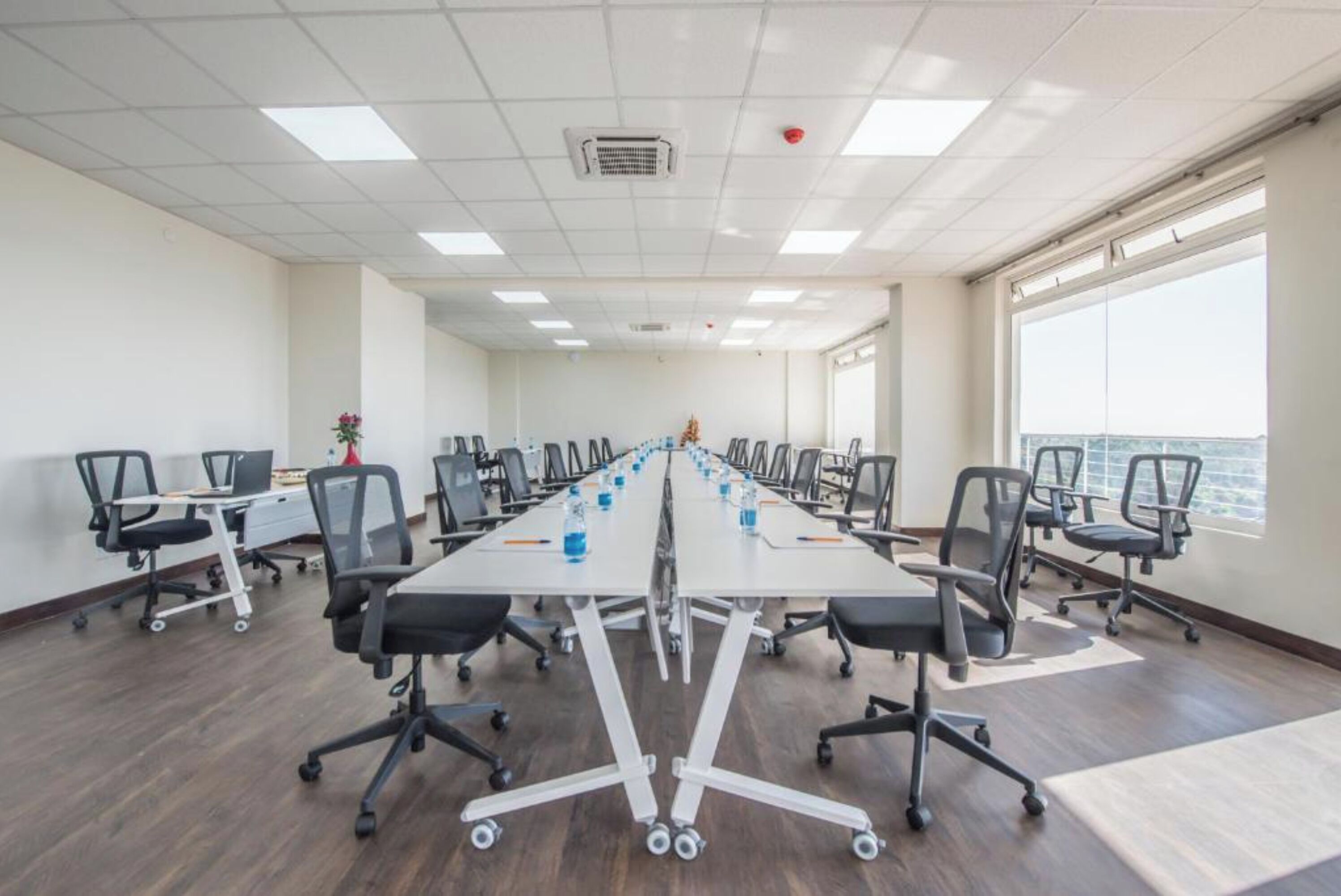 A conference room with a long table, multiple chairs, and a view of the city through large windows.