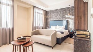 Een hotelkamer met een bed, een slaapbank, een klein tafeltje en een nachtkastje.