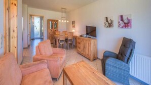 A spacious living area with a wooden dining table, two sofas, a TV, and artwork on the wall. - Tolles Appartment in der Seenplatte (Rechlin)