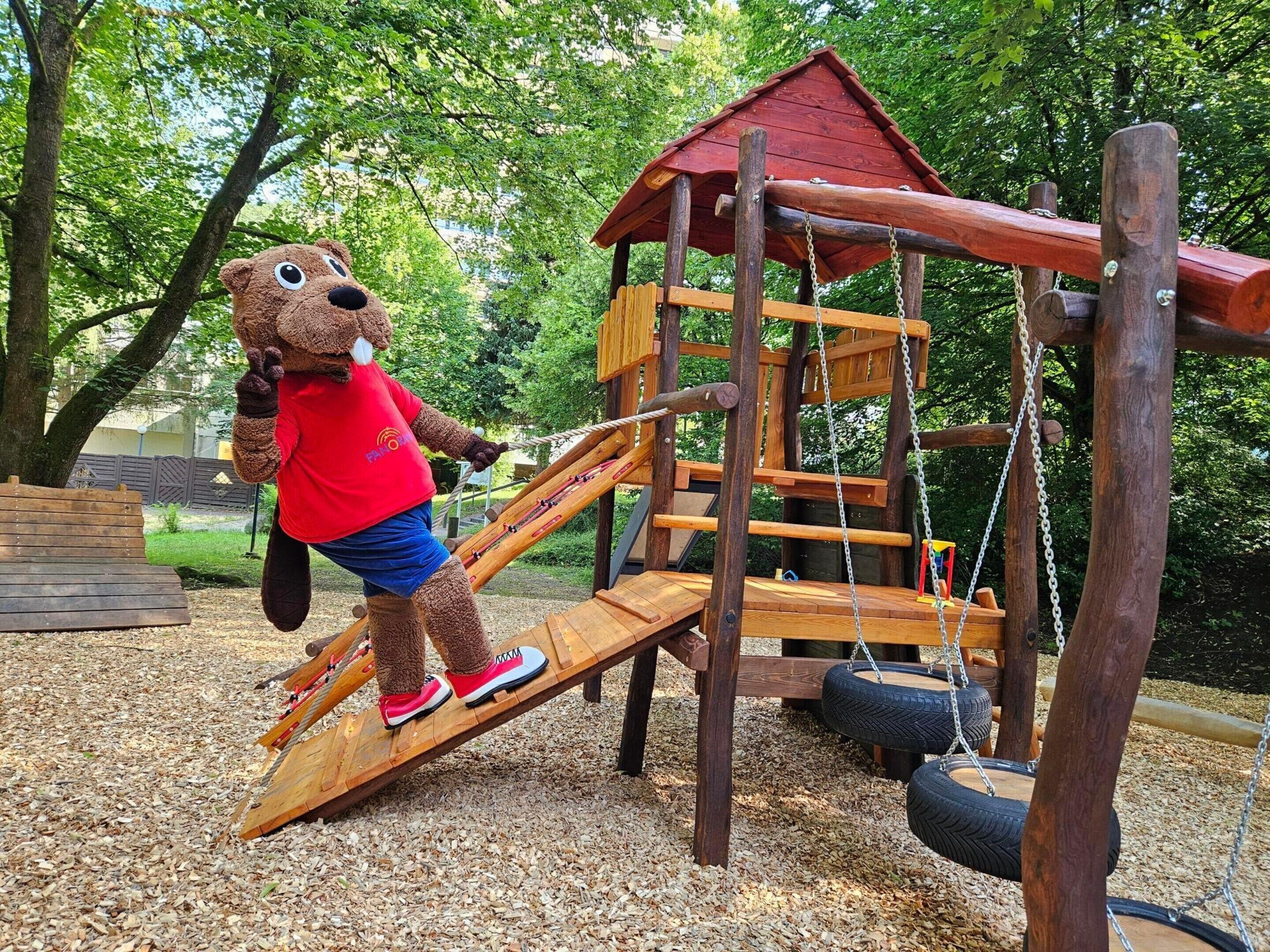 Un parque infantil con una estructura de madera para escalar y un columpio de neumático.