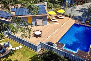 En boligejendom med swimmingpool, solpaneler, en terrasse med udendørs møbler og en lukket have.
