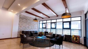 Amplia sala de estar con pared de piedra, ventanas grandes y muebles modernos.