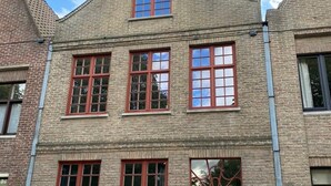 Un bâtiment en briques doté d’une tour centrale, de nombreuses fenêtres aux encadrements rouges et d’une porte rouge.