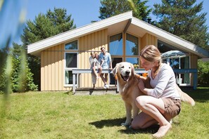 A modern house with a large deck, a covered outdoor seating area, and a grassy yard. - Cottage in Granzow at 500 m From the Lake (Mirow)