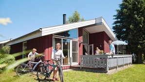 A red building with a white porch and a covered deck. - Cottage in Granzow at 500 m From the Lake (Mirow)