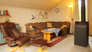 Ein gemütliches Wohnzimmer mit einem braunen Ledersessel, einem braunen Sofa, einem Holztisch und einem Kamin.