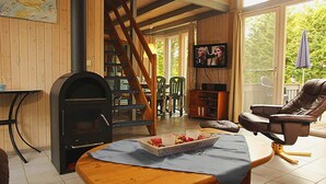 Ein gemütliches Wohnzimmer mit Kamin, Fernseher, Essbereich mit Stühlen und einer Treppe zu einer weiteren Ebene.