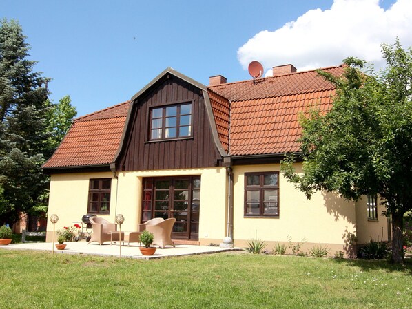 Une maison à deux étages avec un toit brun, des murs de couleur beige et une antenne parabolique.