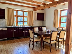 Une cuisine moderne avec des poutres en bois, une table à manger avec des chaises et de grandes fenêtres.