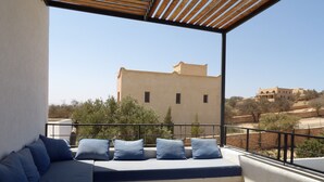 A balcony with a sofa and cushions, a tiled floor, and a view of buildings in the distance. - Air-conditioned villa with private pool 15 minutes from the beaches (Essaouira)