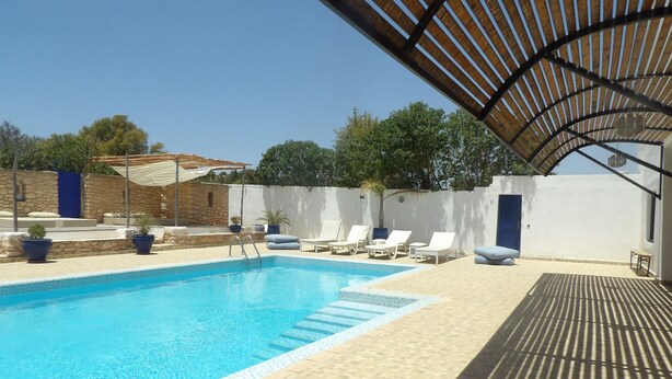 A swimming pool with lounge chairs and a pergola. - Air-conditioned villa with private pool 15 minutes from the beaches (Essaouira)