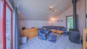 Una sala de estar acogedora con un sofá modular, una mesita y una chimenea de leña.