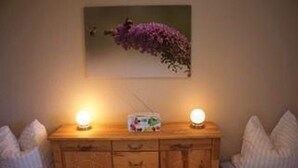 A wooden dresser with two bedside lamps, a radio, and a framed picture on the wall. - Tolles Appartment in der Seenplatte (Rechlin)