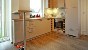 Una cocina moderna con armarios de madera, horno integrado y ventana que proporciona luz natural.