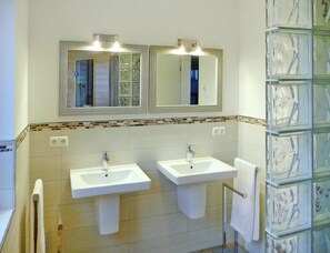 Ein Badezimmer mit zwei Waschbecken, je einem Spiegel darüber und einer Fliesenrückwand.