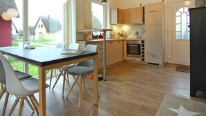 Una cocina moderna con armarios de madera, una mesa de comedor con sillas y vistas al exterior.