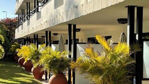 Ett hotell med modern design, med en rad stora krukväxter längs gångvägen och en balkong med ett räcke.