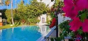 Una piscina rodeada de exuberante vegetación y flores coloridas.