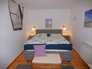 Una camera da letto con un letto, due comodini, un tavolo da notte, una sedia, un termosifone e una parete con un poster.