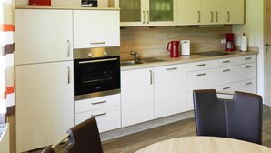 A modern kitchen with white cabinets, a built-in oven, and a coffee maker. - Ferienwohnung Landblick, Rastede (Rastede)