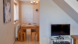 A dining area with a wooden table, chairs, and a chandelier. A television is mounted on the wall, and there is a clock on the wall. - Forest Park Lodge (Umberleigh)