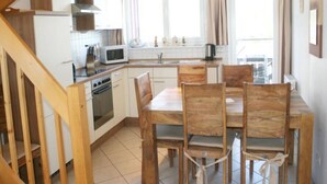 Eine moderne Küche mit weißen Schränken, einer Mikrowelle, einem Backofen und einem Esstisch mit Holzstühlen.