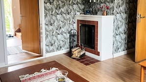 Une pièce avec une cheminée, un papier peint à motifs, un plancher en bois et un tapis.