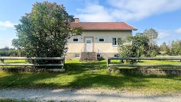 A two-story house with a red-tiled roof, a front door, and a small porch.