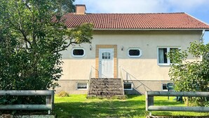 A two-story house with a red-tiled roof, a front door, and a small staircase leading to the entrance. - 4 Person Holiday Home in Tingsryd (Tingsryd)