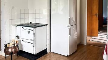 A compact kitchen with a stove, a refrigerator, and a small cabinet.