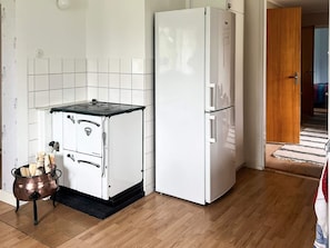 A compact kitchen with a stove, a refrigerator, and a small cabinet.