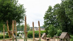 Un parque infantil con estructuras para escalar y una pequeña cabaña de madera.