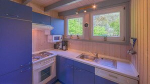 Una cocina pequeña con estufa, microondas y lavamanos.