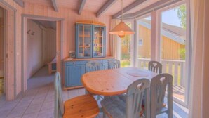 Un interior de madera con una mesa de comedor y sillas, un mueble azul y una lámpara colgante.
