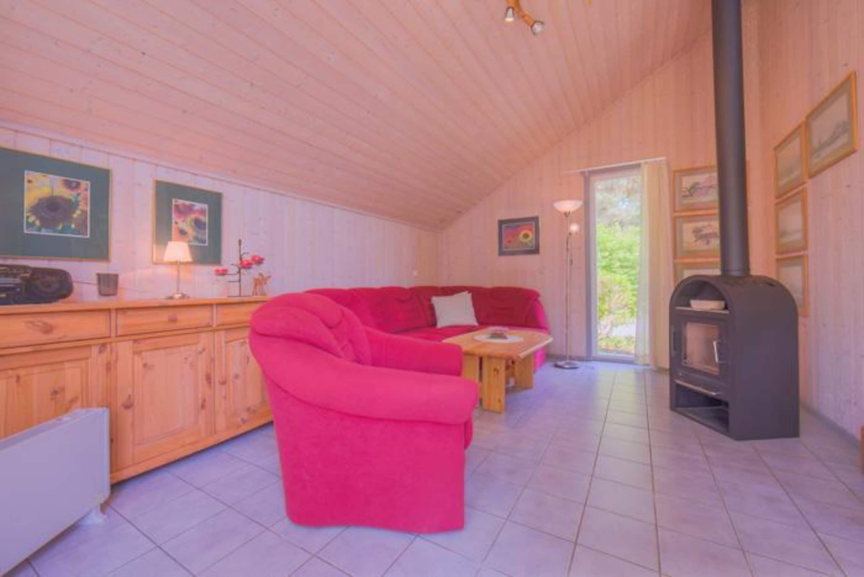 Una habitación acogedora con un sofá rojo, armarios de madera y una chimenea.