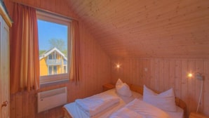 A wooden cabin room with two beds, a window, and a radiator. - Ideales Ferienhaus fur Familien (Rechlin)