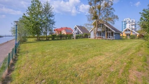 A grassy area with houses, a body of water, and a clear sky. - Ideales Ferienhaus fur Familien (Rechlin)