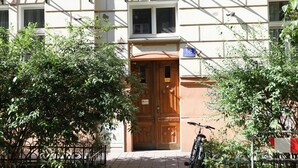 A building entrance with a wooden door, a bicycle parked outside, and a sign indicating the address. - DReAM Post Aparthotel (Kraków)