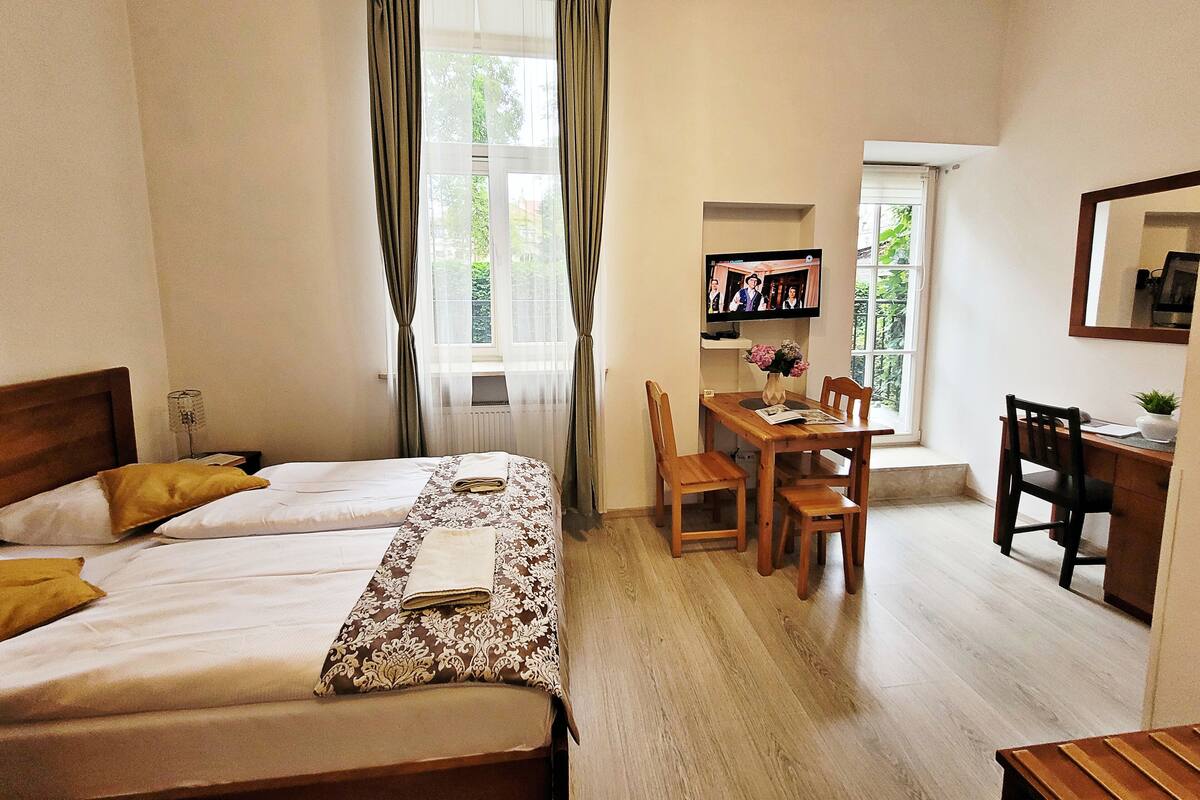 Una camera d'albergo con due letti, una scrivania in legno, una sedia e un televisore.