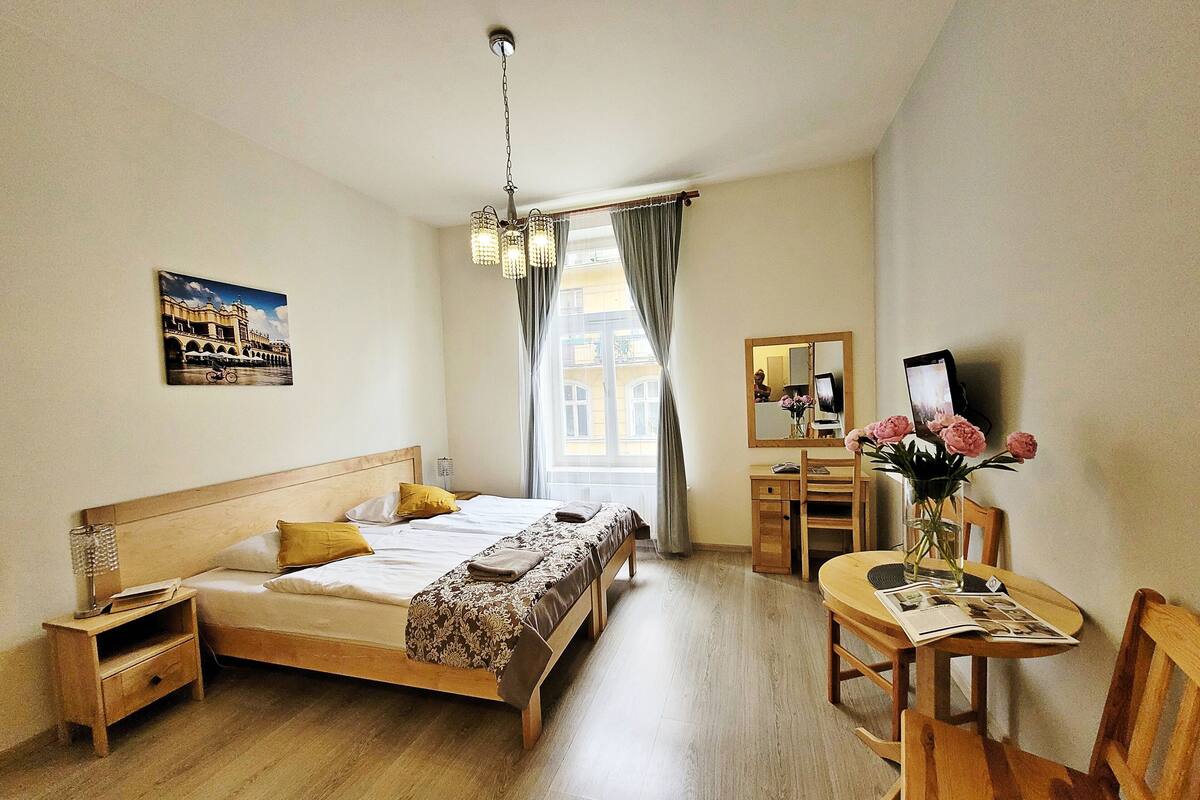 Una camera d'albergo con un letto, comodino, scrivania, sedia e specchio.