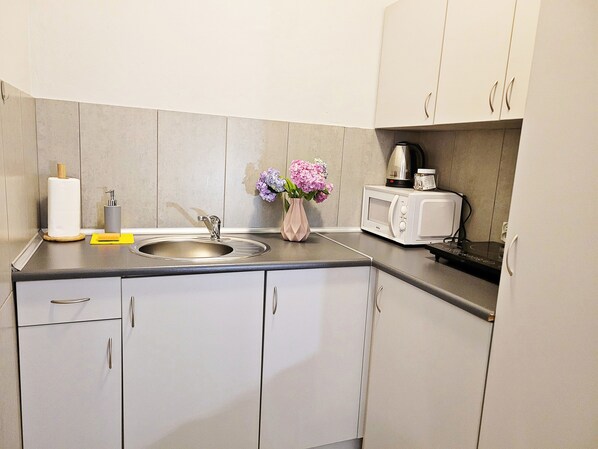 A modern kitchen with a sink, a microwave, and a vase with flowers.