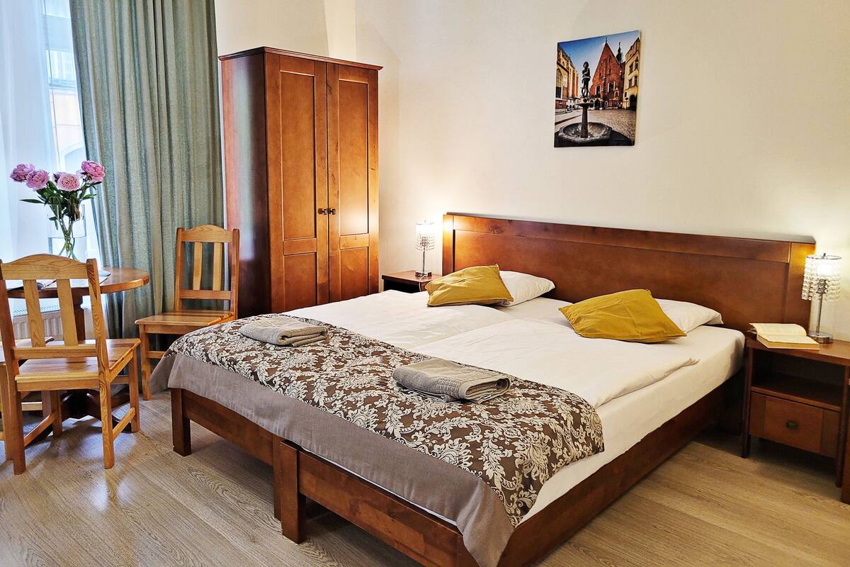 Camera d'albergo con un letto grande, un armadio in legno, una scrivania con una sedia e un quadro appeso al muro.