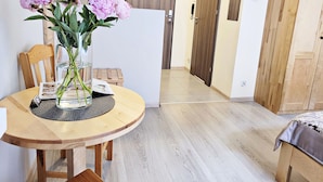 A dining area with a round wooden table, a vase with flowers, and a chair. There is a wooden door and a cabinet in the background. - DReAM Post Aparthotel (Kraków)